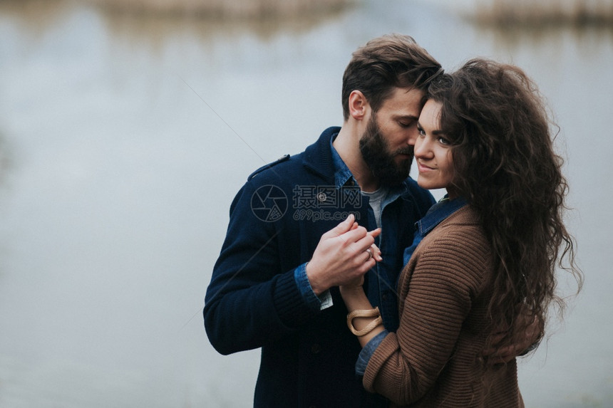 快乐的情侣在湖边年轻的情侣在秋天户外拥抱一个有胡子的男人和卷毛女在爱中情节爱与家庭的概念幸福情侣在湖边年轻夫妇在秋天户外拥抱一个图片