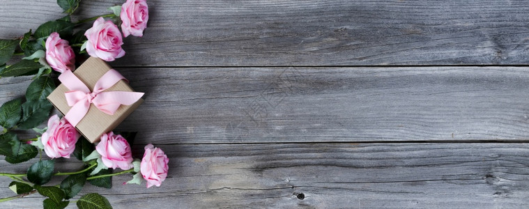 粉红玫瑰和礼物盒上面有风湿的木板母亲节爱假日概念背景图片
