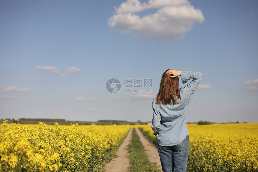 在黄开花的种子田中年轻女性。 在黄开的种子田中年轻女性。图片