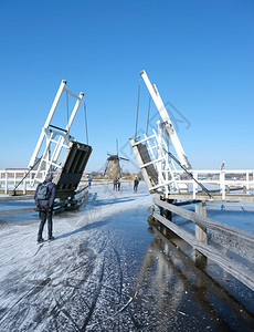 人们在寒冷的水中滑过吊桥在寒冷的冬天图片