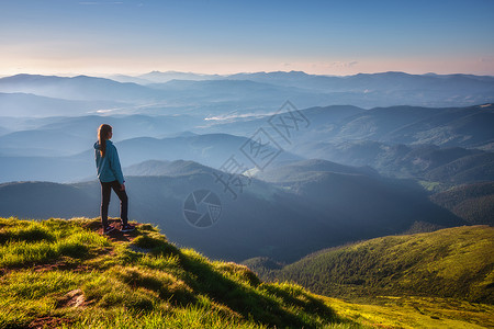 草塔夫茨山顶上的女孩绿色草地看着美丽的山谷夏天日落时雾中风景与运动的年轻女子雾山森林天空旅行和游远足背景