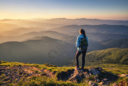 山顶上的女孩绿色草地看着美丽的山谷夏天日落时雾中风景与运动的年轻女子雾山森林天空旅行和游远足背景图片