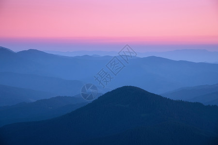 秋天日落时雾中山脊美丽的风景有雾山谷岩石森林红天在黄昏时蓝色钟坠落山的空中景象顶端风自然背背景图片