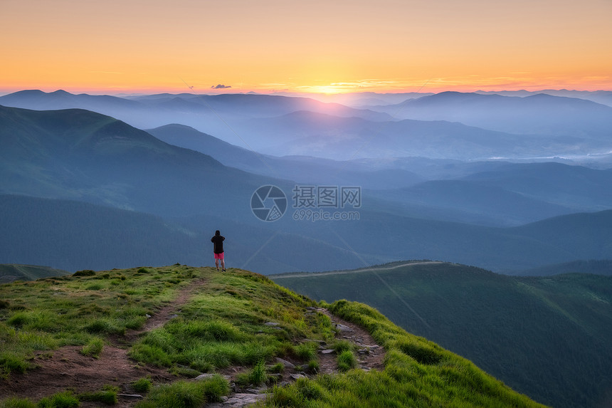 山顶上的运动男子在山峰上仰望着谷在欧洲夏季的多彩日落时阳光照耀着太有旅行者迷雾山森林陷落令人惊叹的天空和阳光风景图片