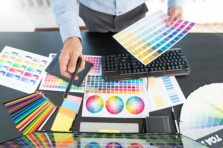 创意图形设计师在办公室工作时为编辑艺术品选择颜色比例图片