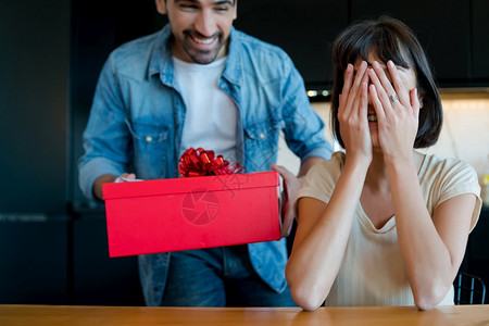 年轻人的肖像用礼物盒给他的女朋友一个惊喜庆祝和情人节白天的概念图片