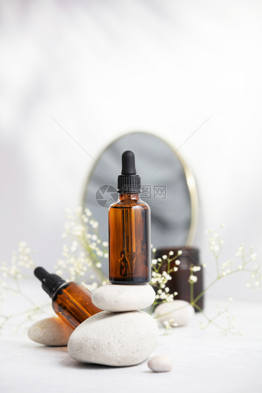 含有天然石头和蜡烛堆叠上基本油的黑黄玻璃瓶子天然有机化妆品芳香治疗信息油图片