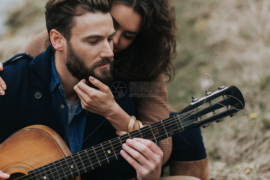 Caucasian男子在湖边与女人一起弹吉他年轻夫妇在秋天户外拥抱一个有胡子的男人和卷毛女在恋爱中ValentineDay爱和家图片