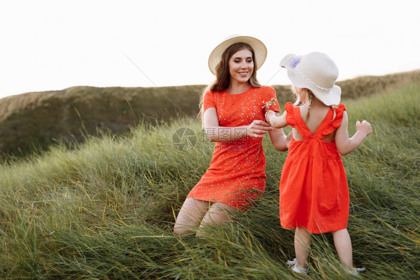 年轻美丽的母亲和小女儿在暑假时大自然中行走母亲和女孩在日落时田里玩耍母亲日友好家庭的概念友好家庭的概念图片