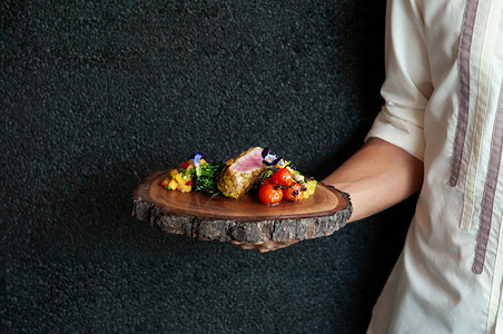 提供用草药和烤蔬菜芒果肉木板上的马铃薯烧烤金鱼牛排的侍者背景图片