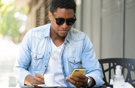 非裔美国人坐在咖啡店时使用手机城市概念图片