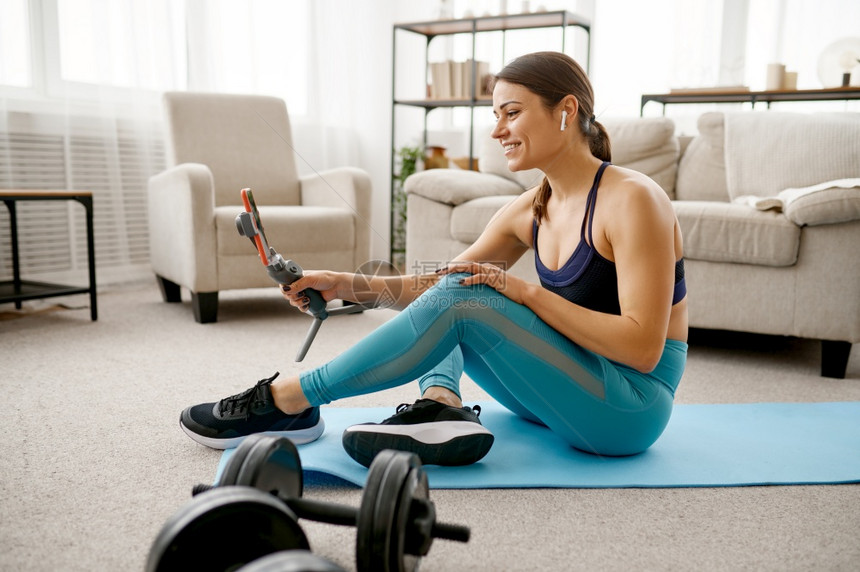 微笑的女孩坐在地板上线健身培训笔记本电脑上女穿运动服网上锻炼室内房间女孩坐在地板上线健身培训图片