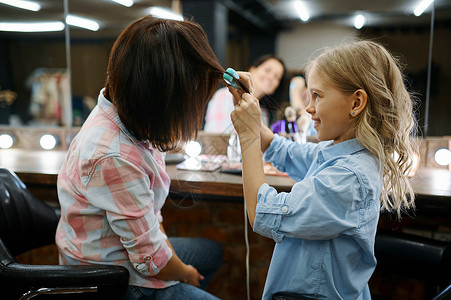 母亲和女儿在发廊理妈和小女孩一起玩理发师快乐的童年迷人家庭母亲和女儿在发廊理背景图片