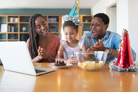 家庭在中用笔记本电脑视频话在网上庆祝生日的肖像背景图片