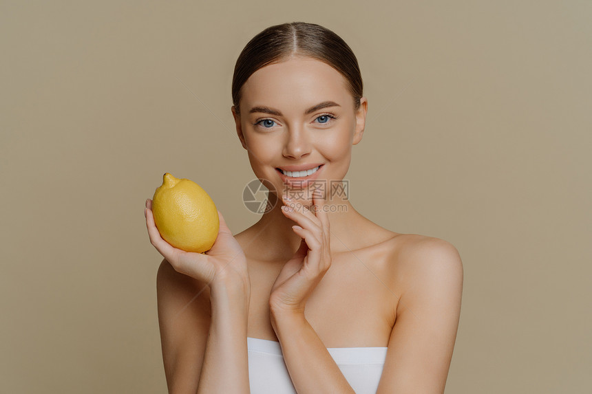 美容学皮肤护理和美容概念穿着浴巾的漂亮黑褐色年轻女人拿着柠檬做面部罩图片
