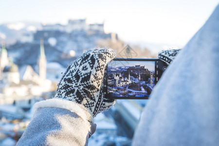 年轻旅游女青正在用她的智能手机拍摄萨尔茨堡的照片图片