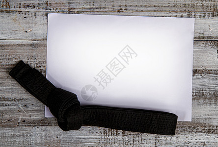黑皮带武术技巧的顶部绑在木背景上并有文字的位置图片
