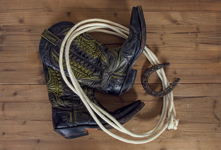 古老的典牛仔靴马蹄和木背景的套索图片
