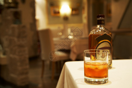 酒精上瘾威士忌的玻璃杯和餐厅桌上的瓶子背景