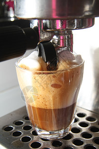 一杯含拿铁马奇亚托的杯子咖啡和蒸牛奶由意大利电管式咖啡机制成图片