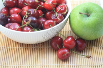 一群多汁新鲜樱桃在白碗和绿苹果里背景图片