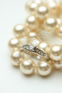 在频道布置和珍珠项链中的钻石订婚戒指图片