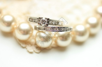 在珍珠项链上戴钻石的订婚戒指和结图片