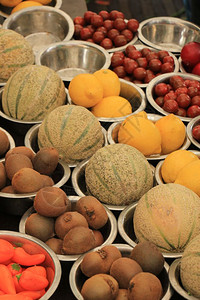 在小金属碗中展示的市场摊位基威瓜和柠檬上的新鲜水果图片