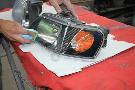 男子用清晰的涂层整修车头灯背景图片