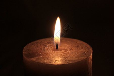 大蜡烛燃烧的特写深色背景图片