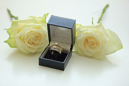 装在盒子和白玫瑰中的订婚戒指图片
