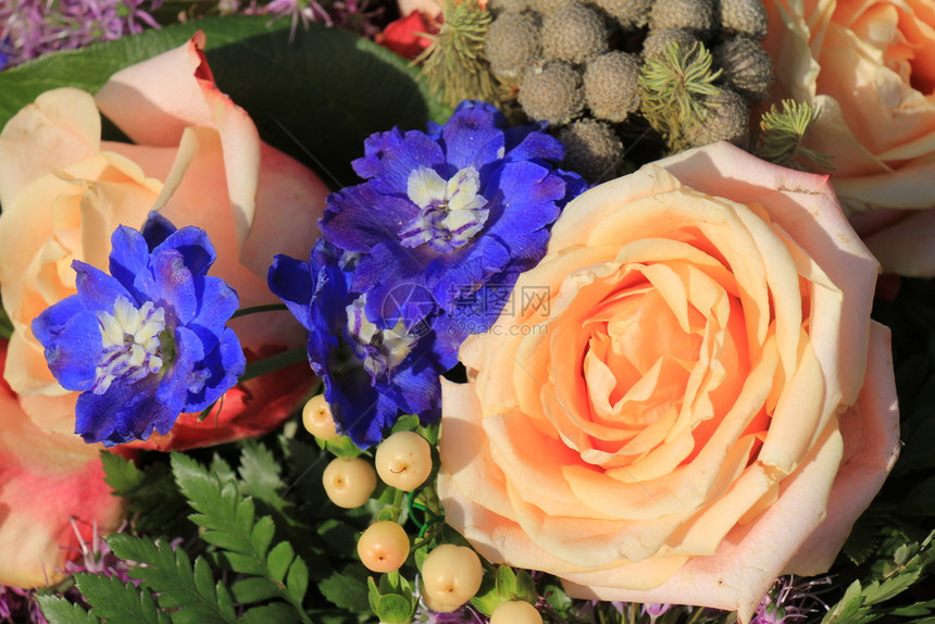 粉红玫瑰和蓝色拉克斯普装在花岗的结婚装饰中图片