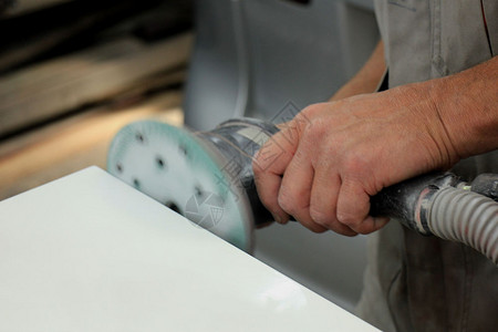 男子在汽车修理间用磨机在汽车零件上磨砂图片