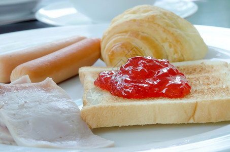 白盘上的早餐烤面包香肠吐司和果酱图片
