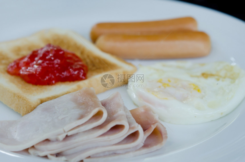白盘上的早餐烤肉煎蛋香肠吐司和果酱图片