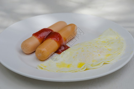 早餐香肠加酱汁和煎蛋在盘子上图片