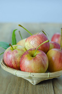 红黄相间的苹果配竹篮白色木质背景有机新鲜水果图片