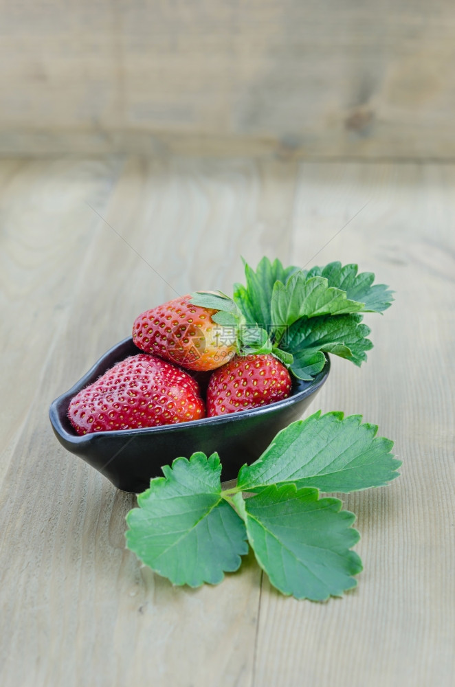 黑碗中新鲜草莓水果木本兼绿叶图片