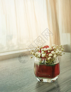 窗帘背景玻璃花瓶中的红玫瑰和白花图片