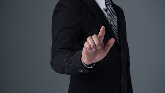 身穿套房的商人用手指着身黑色套房的商人用灰色背景指着手背景图片