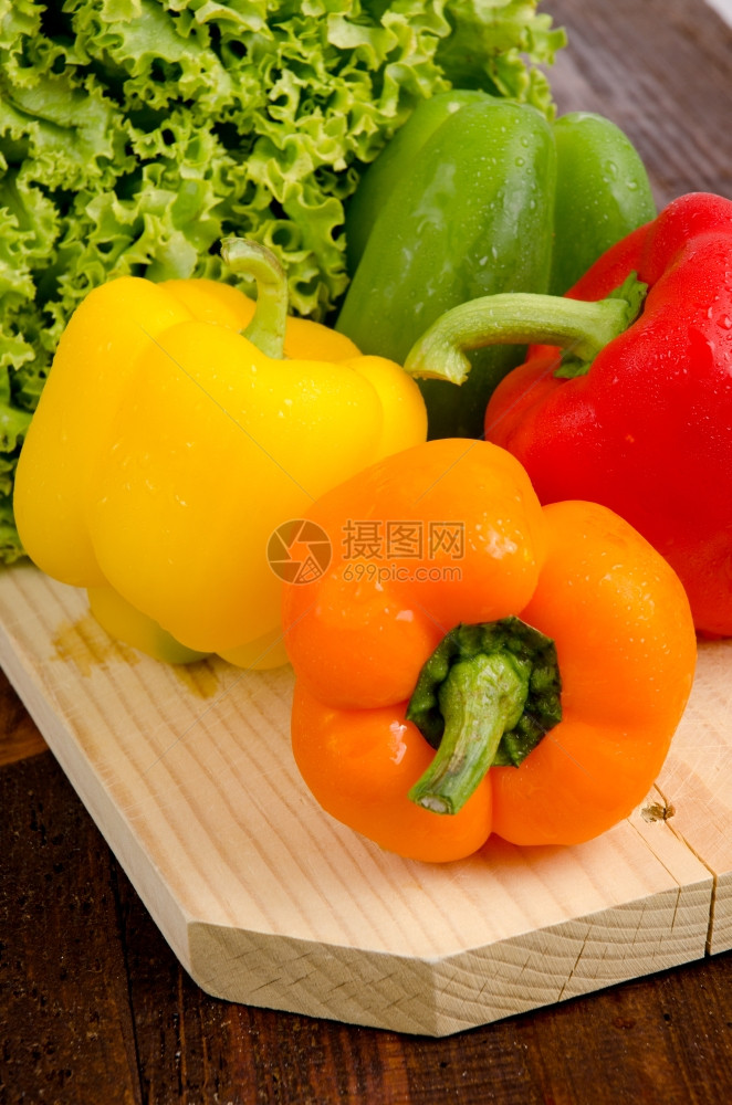 黄色红橙绿胡椒木盘上的生菜图片