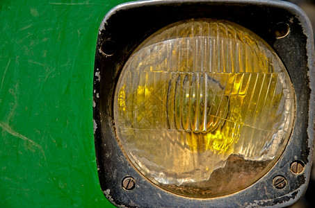 旧拖拉机前黄光照绿漆金属背景近视图片
