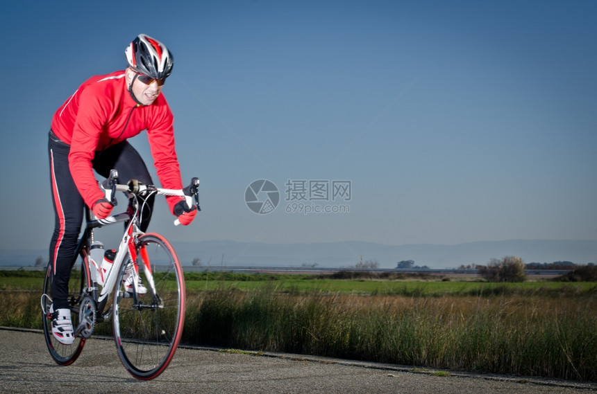 骑着自行车的男子骑着公路在开阔的乡村公路上图片