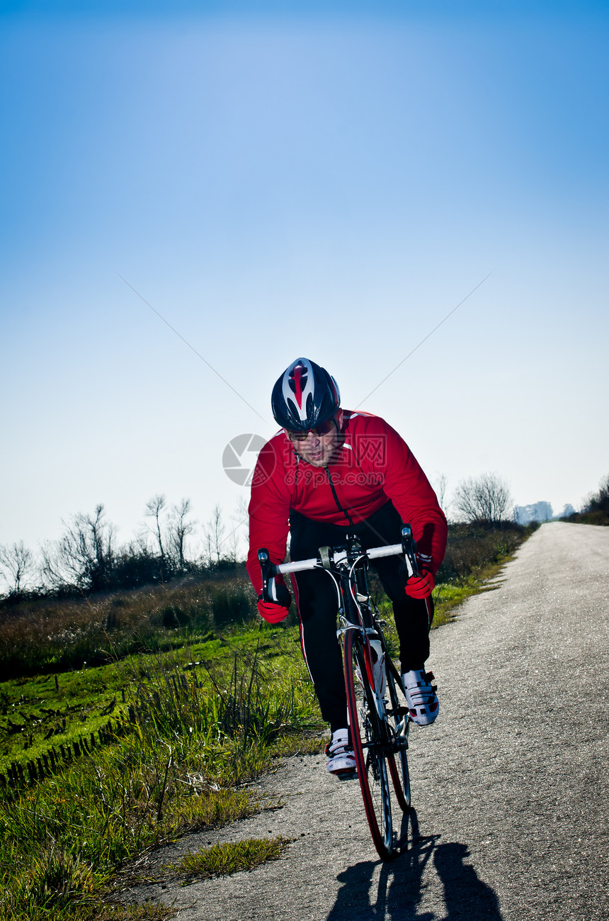 骑着自行车的男子骑着公路在开阔的乡村公路上图片