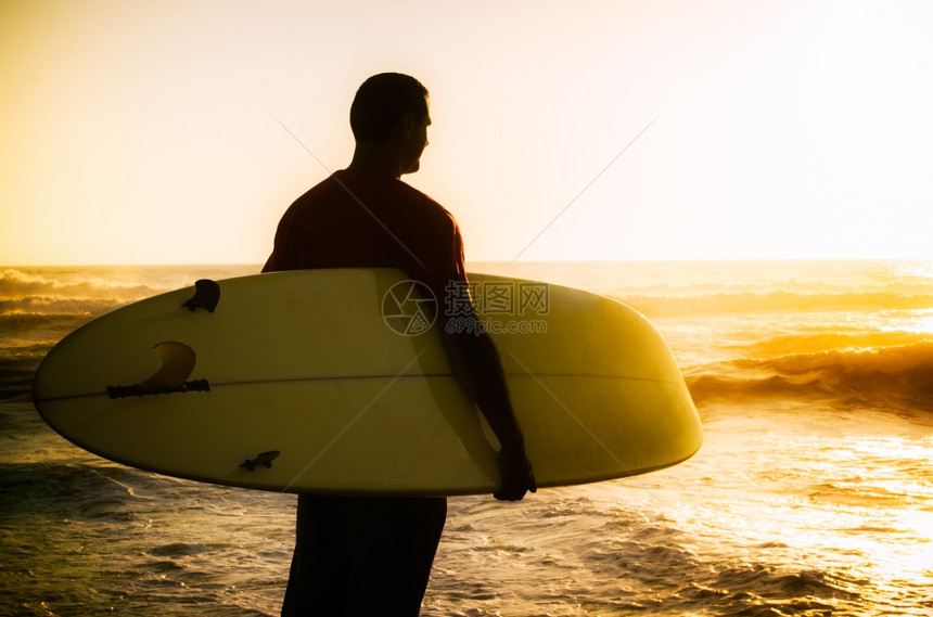 一个在葡萄牙日落时看海浪的冲者图片