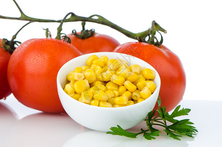 玉米在碗上樱桃西红柿藤在白色背景图片