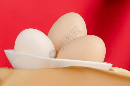 近视图红色背景碗里三个黄色的鸡蛋背景图片