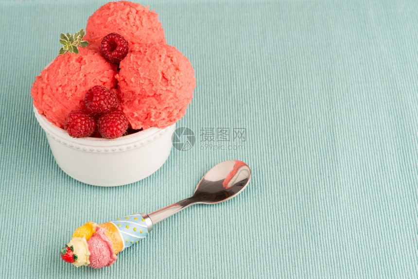 红水果冰淇淋和勺子放在桌背地图片