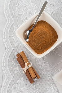 布代利瓷碗上的肉桂棒和粉末背景