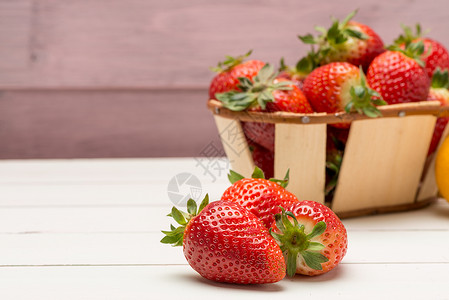 草莓放在木制桌上的小篮子里图片